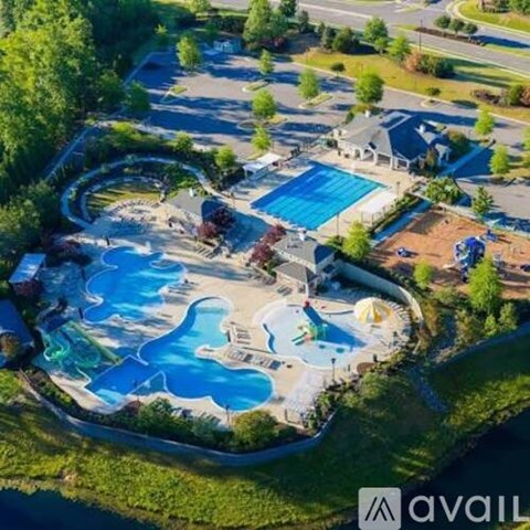 An aerial view of a swimming pool surrounded by trees and a grassy area.