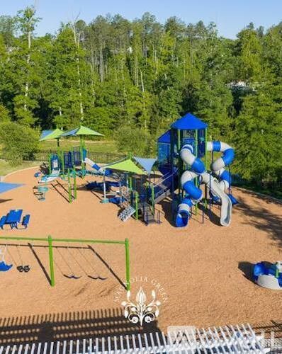 A playground with a blue and white slide and a green umbrella.
