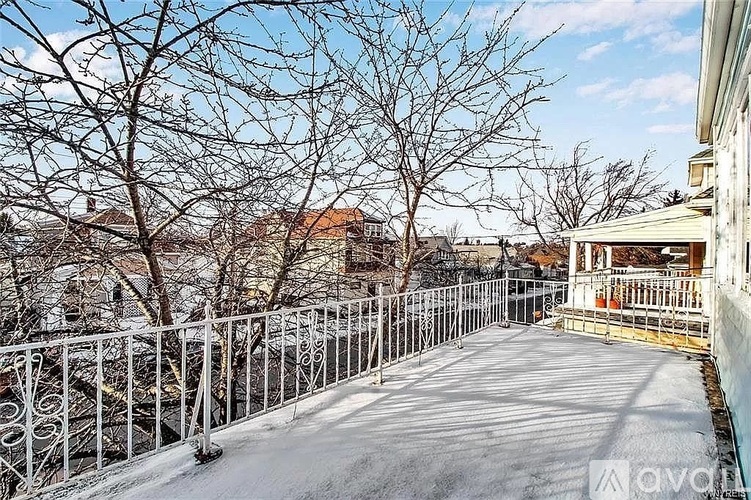 A snow-covered ground with a metal fence and bare trees.