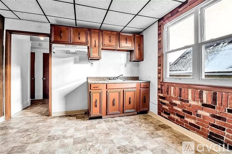 A kitchen with brown cabinets and a brick wall.