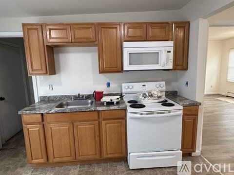 A kitchen with wooden cabinets and a white stove top oven.