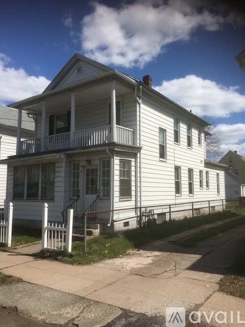 A white two-story house with a porch and a balcony.
