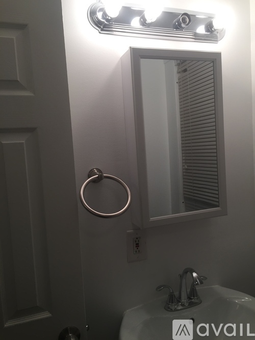 A bathroom with a mirror, sink and light.