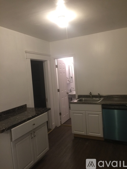 A kitchen with white cabinets and a black counter top.