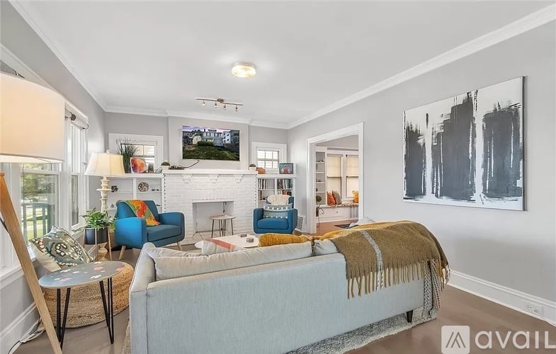 A living room with a white couch and a painting on the wall.