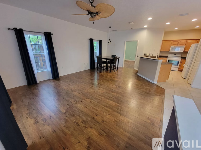 A spacious room with wooden flooring and a ceiling fan.