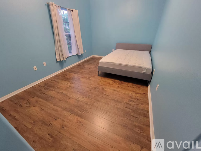A bedroom with a bed and a window with a curtain.