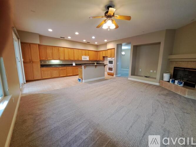 A spacious living room with a fireplace and a ceiling fan.