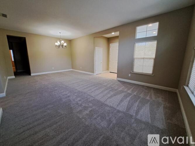 A spacious room with a carpeted floor and a chandelier hanging from the ceiling.