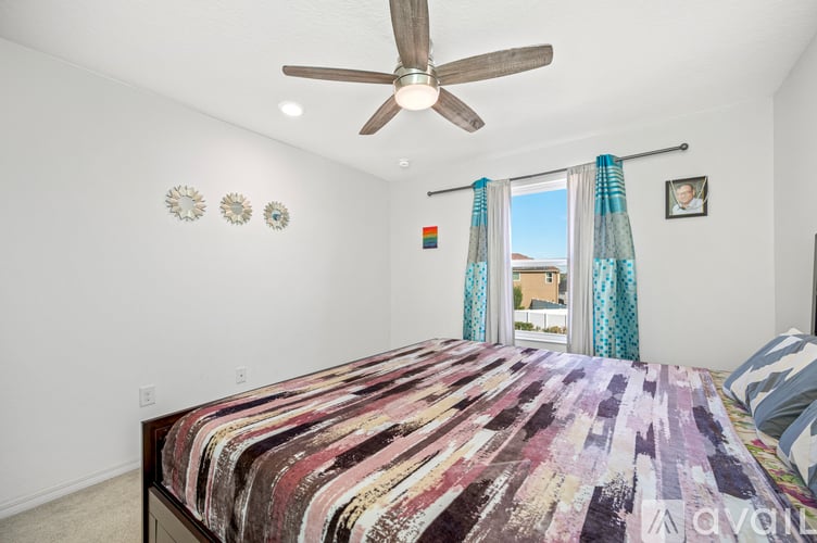 A bedroom with a large bed and a ceiling fan.