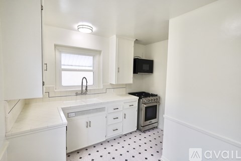 A kitchen with white cabinets and a black and white floor.