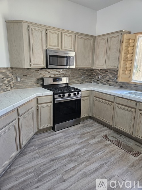 A kitchen with a black stove top oven and wooden cabinets.