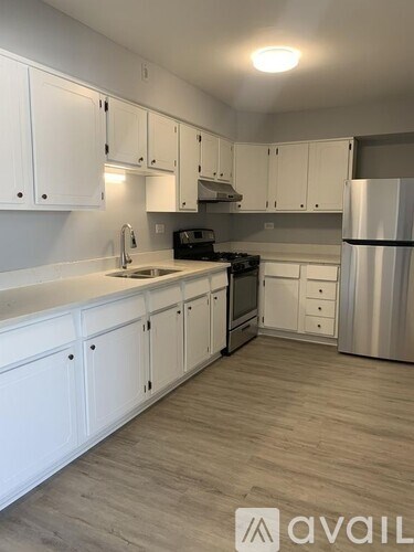 A kitchen with white cabinets and a wooden floor.