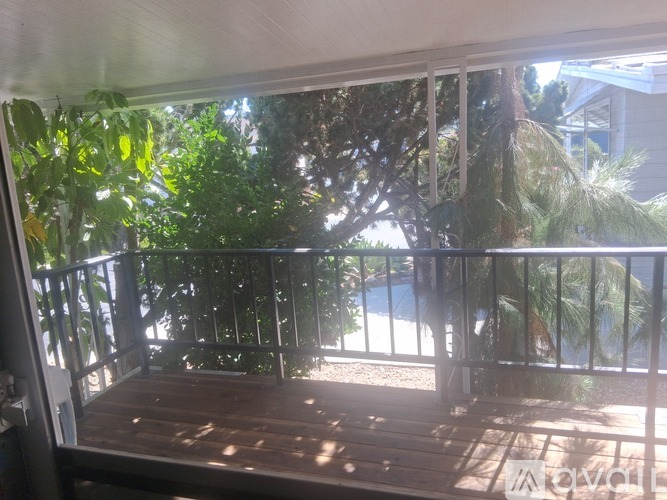 A balcony with a view of a pool and trees.