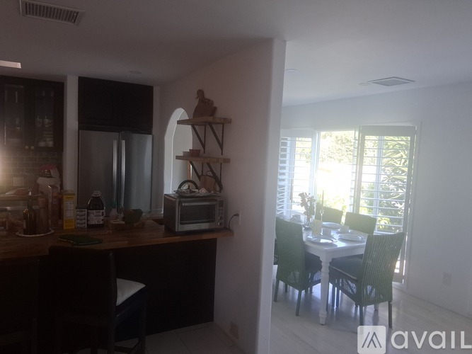 A kitchen with a refrigerator, microwave, and a dining table with chairs.