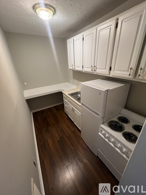 A kitchen with white cabinets and a white stove top oven.