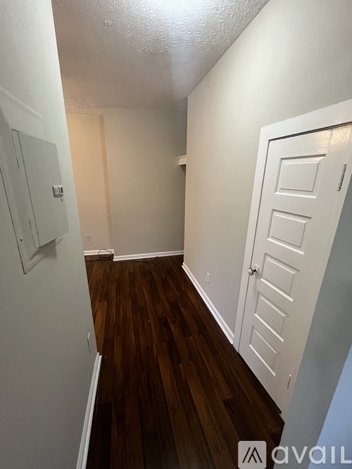 A hallway with a white door and a white wall.