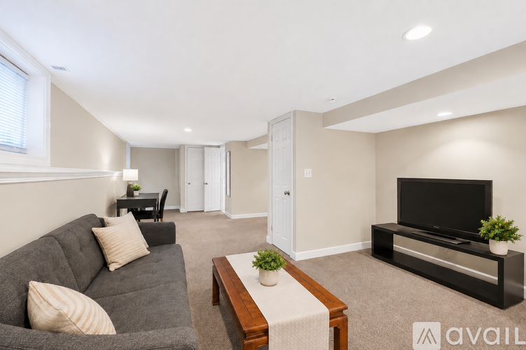 A living room with a grey couch, a wooden coffee table, and a flat screen TV.