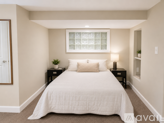 A bedroom with a large bed and a window with a white frame.