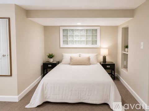 A bedroom with a large bed and a window with a white frame.