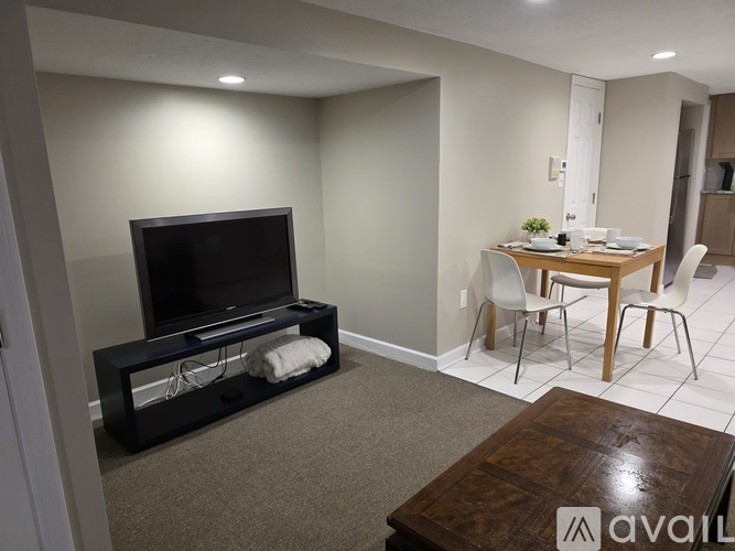 A living room with a flat screen TV and a dining table with chairs.