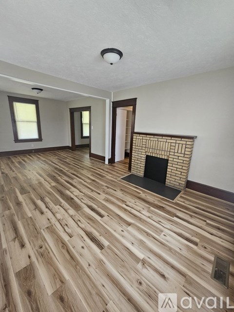 A room with wooden flooring and a fireplace.