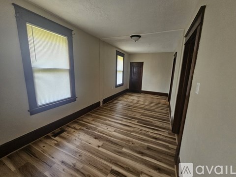 A room with wooden flooring and a window with blinds.