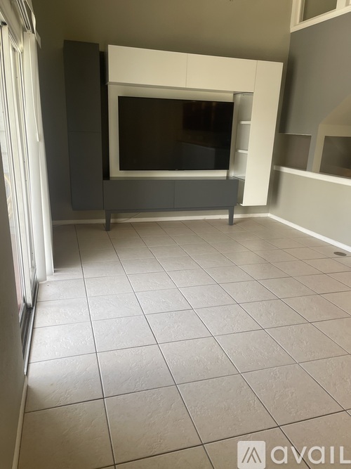 A living room with a television and tiled flooring.