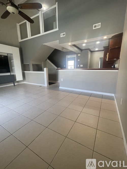 A spacious room with a ceiling fan and tiled flooring.