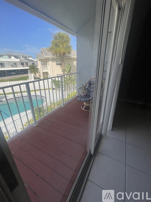 A balcony with a pool and houses in the background.