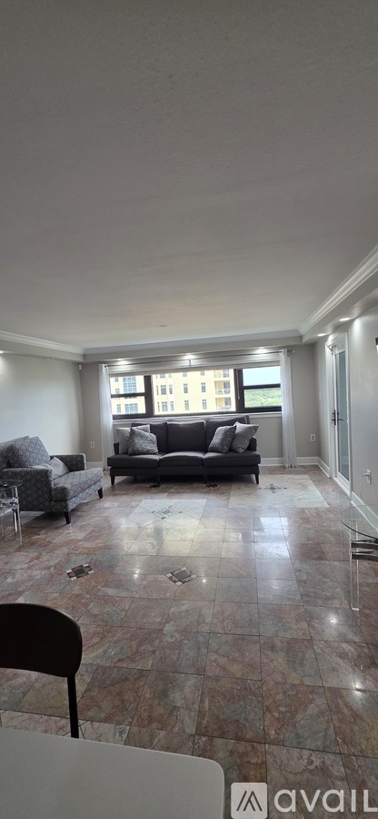 A living room with a couch, chairs, and a large window.