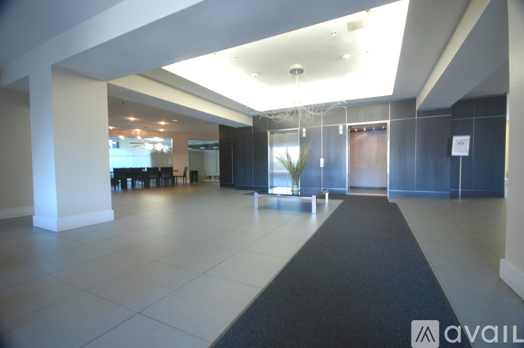 A spacious office lobby with a black carpet leading to a glass door.
