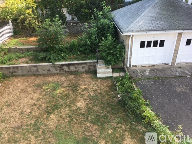 A backyard with a white fence and a small building.
