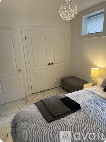 A bedroom with a bed, a chandelier, and a window.