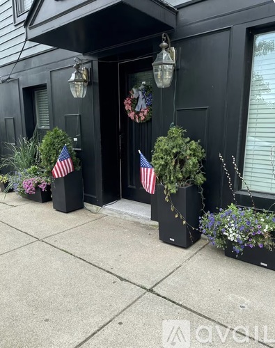 A black building with American flags and plants in front.