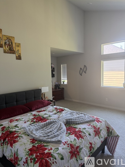 A bedroom with a bed covered in a floral print bedspread and two red pillows.