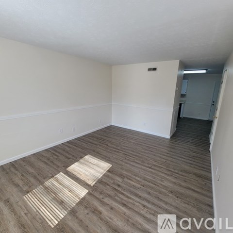 A room with wooden flooring and a door on the right.
