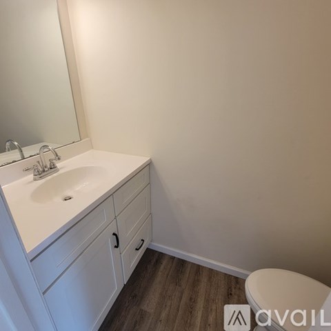 A white sink with a mirror above it and a toilet to the right.