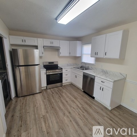 A kitchen with white cabinets and a wooden floor.