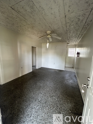 A room with a ceiling fan and a door.