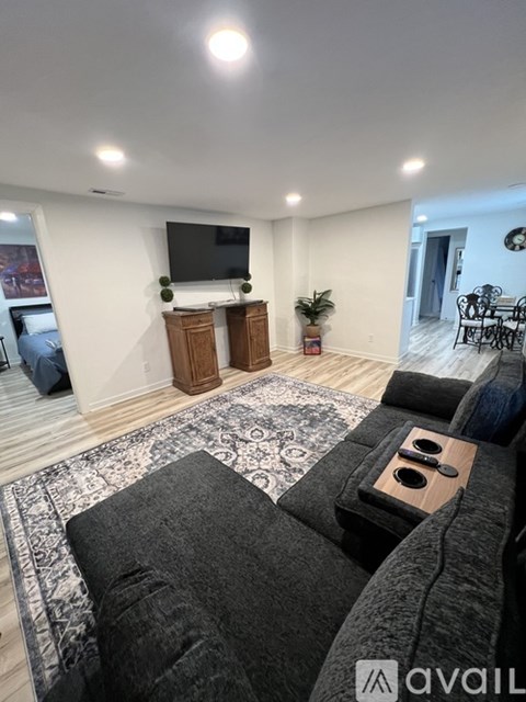 A living room with a grey couch and a television on a wooden stand.