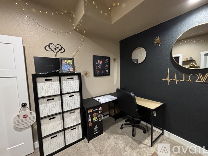 A black and white office space with a desk, chair, and shelving unit.