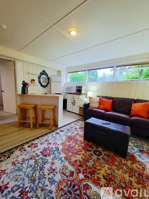 A living room with a brown couch and a rug with a floral pattern.