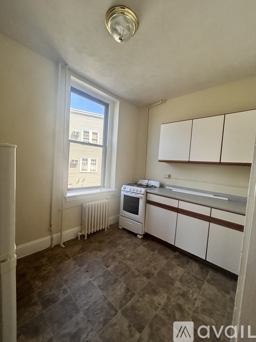 A kitchen with white cabinets and a window.