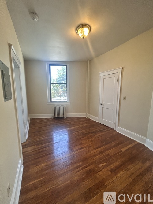 A room with wooden floors and a window with a view of trees outside.
