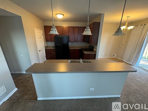 A kitchen with a black refrigerator and wooden cabinets.