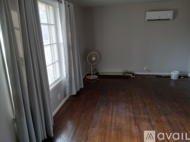 A room with a fan and a window with curtains.