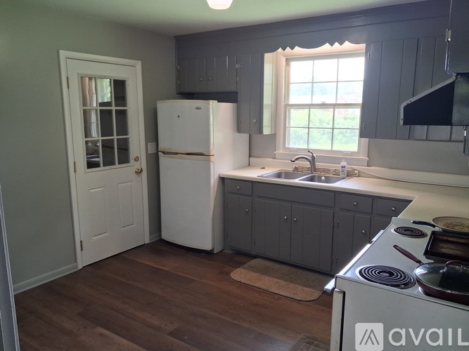 A kitchen with a white refrigerator and wooden floors.