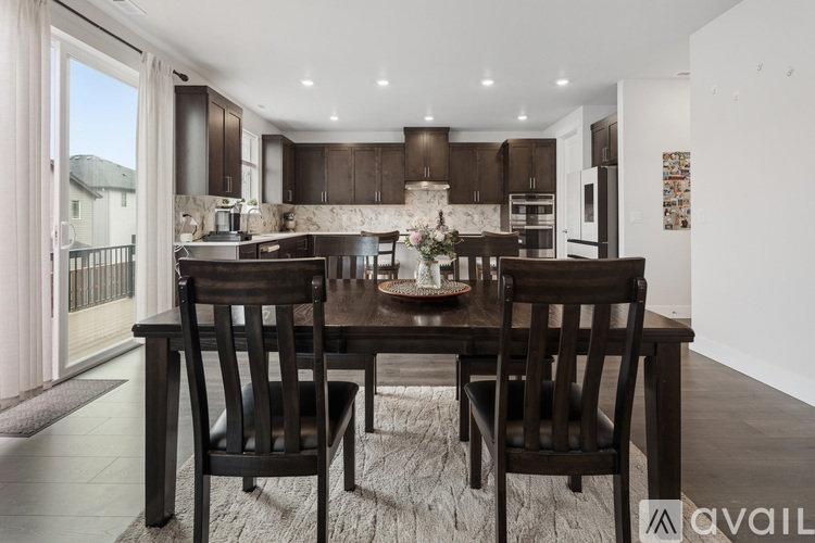 A modern kitchen with dark brown chairs and a dining table.