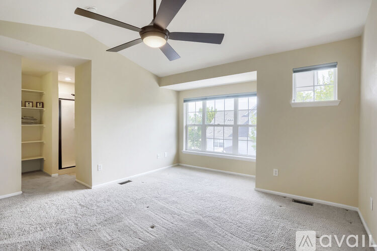 A spacious room with a ceiling fan and a large window.